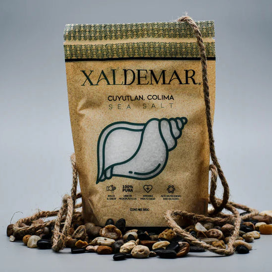envase de la marca de sal marina Xaldemar, sobre piedras pequeñas y cordel