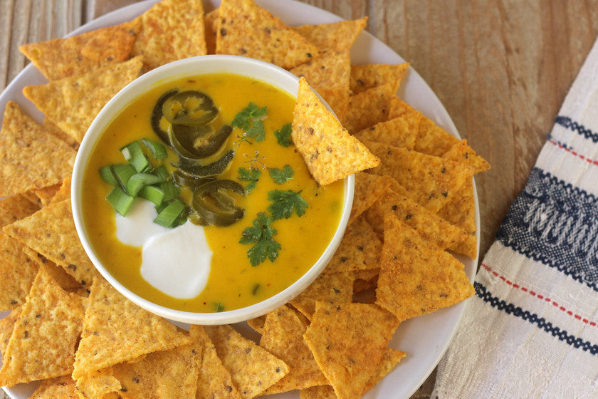 Crema de queso cheddar decorada con jalapeños, cebolla y perejil, acompañada de totopos.