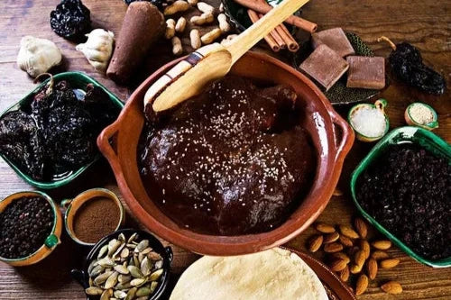 Ingredientes del mole en un tazón de barro, resaltando el color oscuro del mole y los ingredientes tradicionales.