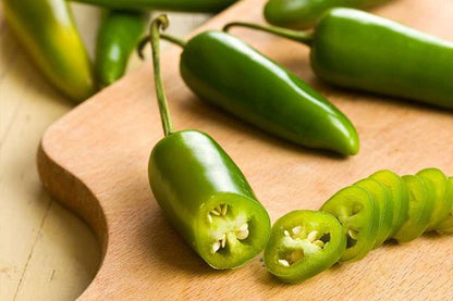 Chiles jalapeños frescos cortados sobre una tabla de madera, ideales para usar en guarniciones y platillos mexicanos.