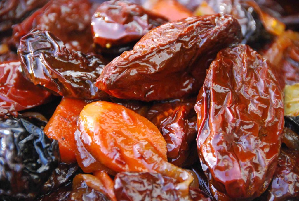 Primer plano de chipotles en adobo, mostrando su textura brillante y jugosa con trozos de zanahoria en el preparado.