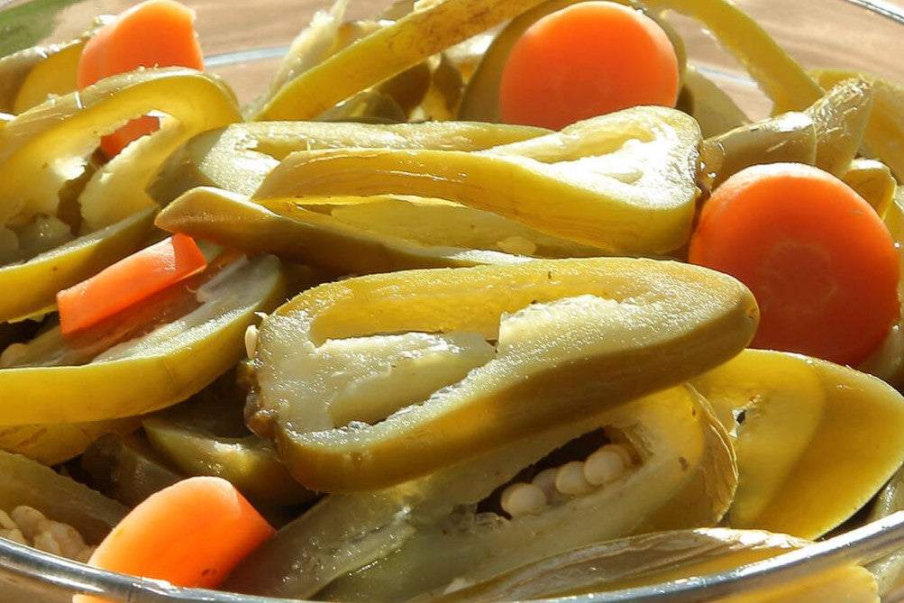 Rodajas de jalapeños en escabeche con zanahorias, mostrando su frescura y sabor perfecto para botanas o guarniciones.