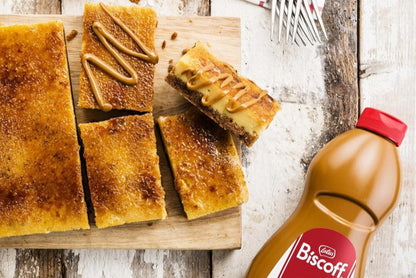vista cenital de un pastel adornado con el topping de crema de galletas biscoff y el bote exprimible al lado inclinado sobre base de madera