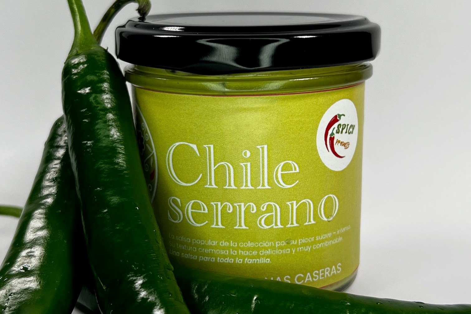 Frasco de salsa acompañado por chiles serranos frescos para destacar su autenticidad.