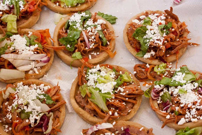 Sopes preparados con carne, lechuga y queso fresco, ideales para fiestas mexicanas