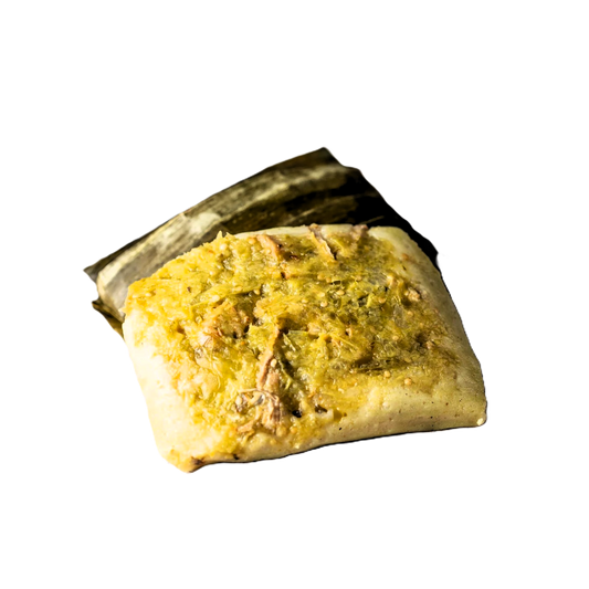 Delicioso tamal con salsa verde, carne jugosa y envuelto en hoja de plátano.