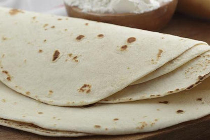 Tortillas de harina sobre una mesa con ingredientes básicos como harina y rodillo.