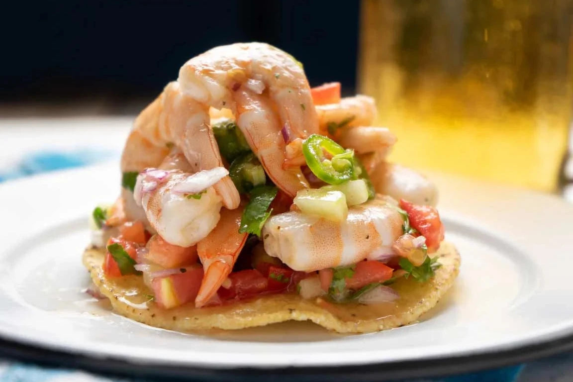 Tostada crujiente con camarones frescos marinados en pico de gallo, acompañada de limón.